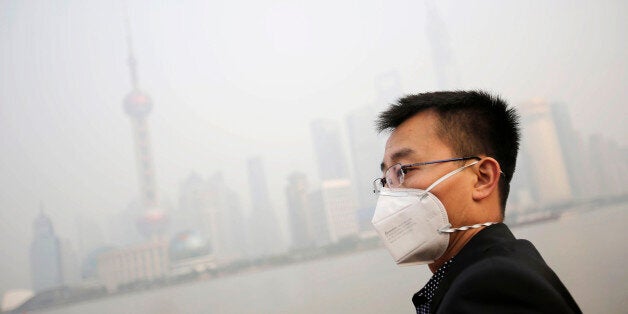 A tourist wearing a protective mask looks at buildings at the Bund under heavy haze in Shanghai, China, Friday, Dec. 20, 2013