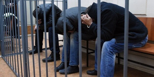 Three unidentified suspects detained over the killing of Russian opposition activist Boris Nemtsov hide their faces inside th