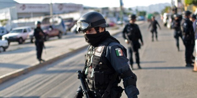 Federal Police Officers are seen near an abandoned car with two corpses in its trunk in Acapulco, Mexico on December 18, 2014. Guerrero is one of Mexico's poorest and most violent states, where a lucrative drug trade has flourished. Drug trafficking in the state is dominated by the Los Rojos criminal gang, based in the regional capital Acapulco. AFP PHOTO/ Pedro PARDO (Photo credit should read Pedro PARDO/AFP/Getty Images)