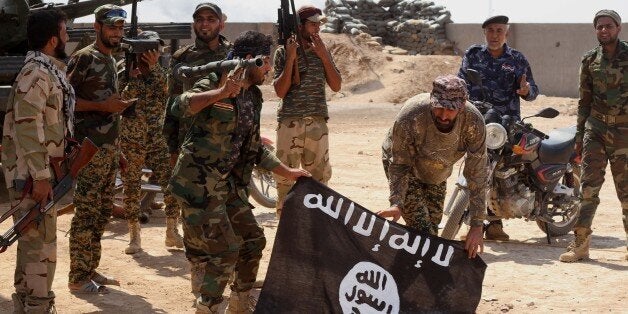 FILE - In this Tuesday, Oct . 7, 2014 file photo, Iraqi security forces hold a flag of the Islamic State group they captured during an operation outside Amirli, some 105 miles (170 kilometers) north of Baghdad, Iraq. The fight against the Islamic State has deepened the bond between Iraqâs Shiite-led government and Iran, to the extent that Iran has easily eclipsed the United States in the eyes of many Iraqis as the main ally in defeating the extremists. (AP Photo, File)