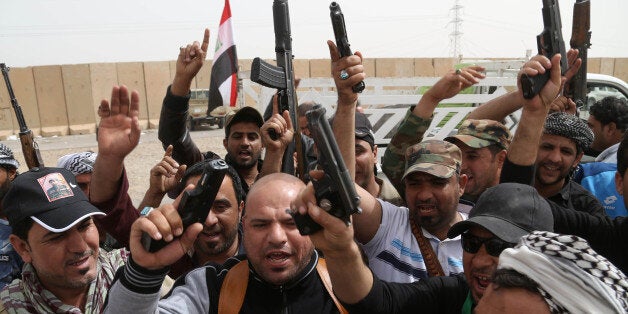 Iraqi Shiite militiamen chant slogans during clashes with the Islamic State group in Tikrit, 130 kilometers (80 miles) north of Baghdad, Iraq, Friday, March 13, 2015. Iraqi forces entered Tikrit for the first time on Wednesday from the north and south. On Friday, they fought fierce battles to secure the northern Tikrit neighborhood of Qadisiyya and lobbed mortars and rockets into the city center, still in the hands of IS. Iraqi military officials have said they expect to reach the center of Tikrit within two to three days. (AP Photo/Khalid Mohammed)