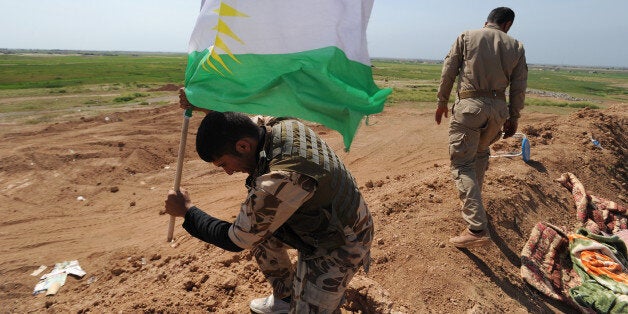 KIRKUK, IRAQ - MARCH 13: A peshmerga fighter plants a Kurdish flag atop a new earth berm position as Iraqi Kurdish forces pus