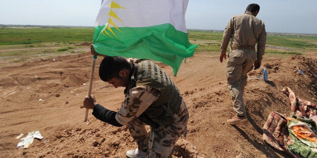 KIRKUK, IRAQ - MARCH 13: A peshmerga fighter plants a Kurdish flag atop a new earth berm position as Iraqi Kurdish forces push the frontline forward against ISIS forces in the Tal al-Ward district 20 miles southwest of Kirkuk, Iraq, on March 13, 2015. These peshmerga units of the Patriotic Union of Kurdistan (PUK) faction have made significant gains against villages held by ISIS, in concert with an Iraqi government and Shiite militia attack further south to free Tikrit from ISIS control, with a joint aim of squeezing the jihadist militants from Iraq. Since ISIS swept from Syria in June, 2014, Kurdish forces in northern Iraq have expanded their control over oil-rich territories disputed with Baghdad such as Kirkuk and its oil and gas facilities. (Photo by Scott Peterson/Getty Images)