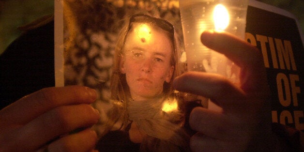 A Palestinian man holds a candle and a picture of American peace activist Rachel Corrie during a memorial service in the West Bank town of Ramallah Tuesday, March 18, 2003. Corrie, a native of Olympia, Wash., was killed in the Gaza Strip city of Rafah Sunday as she tried to block an Israeli bulldozer as it destroyed a Palestinian home. (AP Photo/Muhammed Muheisen)