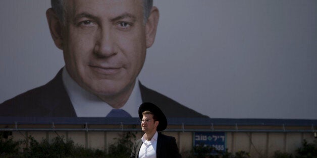 An Orthodox Jewish man walks past a billboard of Israeli Prime Minister Benjamin Netanyahu in Bnei Brak near Tel Aviv, Israel, Monday, March 16, 2015, a day ahead of legislative elections. Netanyahu is seeking his fourth term as prime minister. (AP Photo/Ariel Schalit)