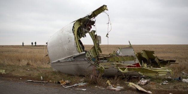 Journalists walk behind parts of the Malaysia Airlines plane Flight MH17 as Dutch investigators (unseen) arrive near at the crash site near the Grabove village in eastern Ukraine on November 11, 2014, hoping to collect debris from the Malaysia Airlines plane which crashed in July, killing 298 people, in remote rebel-held territory east of Donetsk. The Dutch team hopes to begin work as soon as possible amid fears all-out fighting could break out again. AFP PHOTO / MENAHEM KAHANA (Photo credit should read MENAHEM KAHANA/AFP/Getty Images)