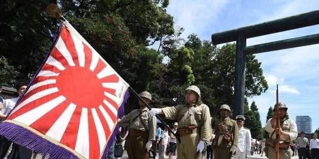 Men clad in Japanese Imperial Army and Navy uniforms stand at attention at the entrance to the controversial Yasukuni shrine