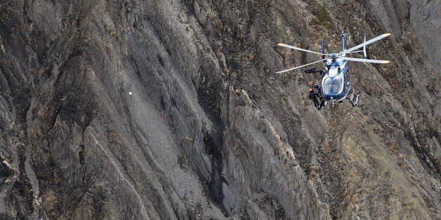 A helicopter carries investigators near scattered debris on the crash site of the Germanwings Airbus A320 that crashed in the French Alps above the southeastern town of Seyne. The young co-pilot of the doomed Germanwings flight that crashed on March 24, appears to have 'deliberately' crashed the plane into the French Alps after locking his captain out of the cockpit, but is not believed to be part of a terrorist plot, French officials said on March 26, 2015. AFP PHOTO / ANNE-CHRISTINE POUJOULAT (Photo credit should read ANNE-CHRISTINE POUJOULAT/AFP/Getty Images)