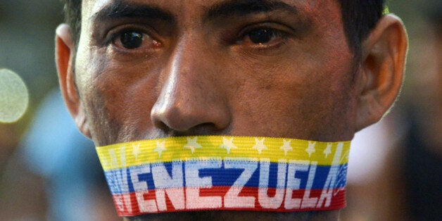 A man attends a protest against the government of Venezuelan President Nicolas Maduro in Caracas on February 23, 2014. A total of 25 people were injured overnight during clashed between opposition groups and police in eastern Caracas. On Saturday the lasgest opposition rally had taken place after almost three weeks of students protests, which left ten people killed. AFP PHOTO/ Raul Arboleda (Photo credit should read RAUL ARBOLEDA/AFP/Getty Images)