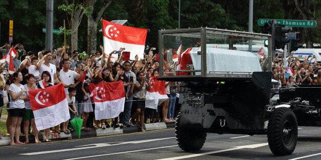 SINGAPORE - MARCH 29: People react as the cortege of the late Mr Lee Kuan Yew passes by Upper Thomson Road on its way for a private cremation service at Mandai Crematorium on March 29, 2015 in Singapore. Mr Lee Kuan Yew passed away on the morning of March 23, 2015 at Singapore General Hospital at the age of 91. Lee Kuan Yew was a Singaporean politician and the first Prime Minister of the country, governing for over 30 years and famed for his achievements in bringing a third world country to first world status in a single generation. (Photo by Suhaimi Abdullah/Getty Images)