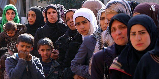 Palestinian refugees wait to collect aid parcels distributed by the United Nations Relief and Works Agency for Palestine Refugees (UNRWA) at the Yarmuk refuge camp, south of Damascus, on March 10, 2015. UNRWA resumed humanitarian assistance distribution after three months of interruption. Yarmuk is now devastated, and only around 40,000 people remain of the 150,000 Palestinian and Syrian people who lived at the camp before the conflict erupted in March 2011. AFP PHOTO / YOUSSEF KARWASHAN (Photo credit should read YOUSSEF KARWASHAN/AFP/Getty Images)