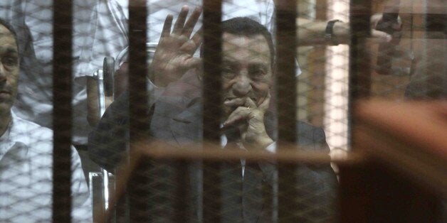 Egypt's deposed president Hosni Mubarak waves from behind the accused cage during his trial on May 21, 2014 in Cairo. An Egyp