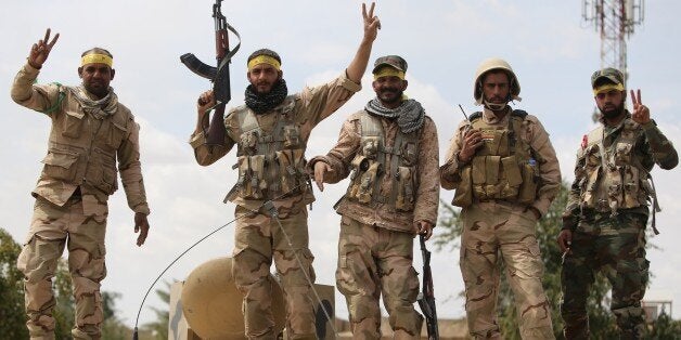 Shiite fighters from the Popular Mobilisation units flash the sign for victory in Tikrit on April 1, 2015, a day after the Iraqi Prime Minister Haider al-Abadi declared victory in the weeks-long battle to retake the northern Iraqi city from the Islamic State (IS) group. Iraqi forces battled the last jihadists in Tikrit to seal a victory the government described as a milestone in efforts to rid the country of the jihadist group. AFP PHOTO / AHMAD AL-RUBAYE (Photo credit should read AHMAD AL-RUBAYE/AFP/Getty Images)