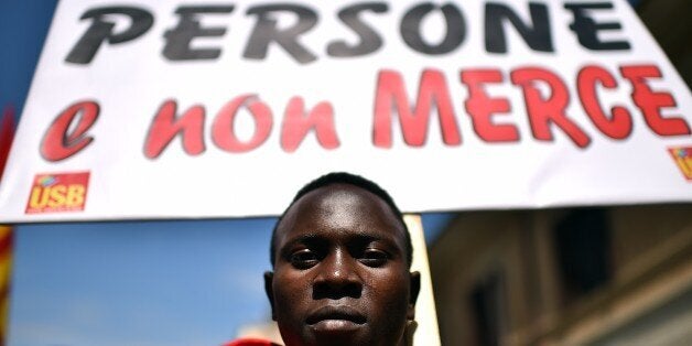 A demonstrator displays a placard which translates as 'We are People, no Goods' during a demonstration by asylum-seeking immi