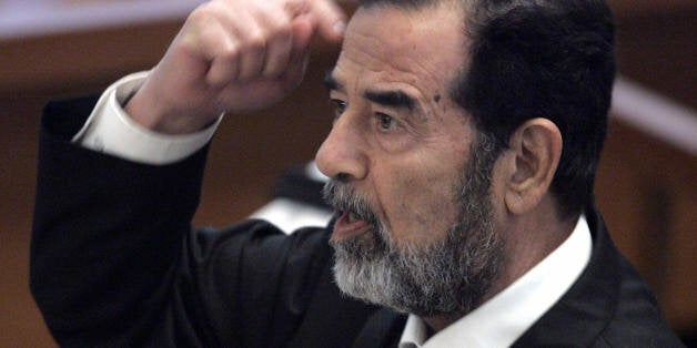 Baghdad, IRAQ: Former Iraqi President Saddam Hussein gestures while addressing the court in Baghdad's heavily fortified Green Zone 11 September 2006 as his trial resumes on charges of genocide against the Kurds during the Anfal campaign of the late 1980s. The trial resumed after a three-week recess, on the day the United States marks the fifth anniversary of the 9/11 attacks and three days after a US senate report concluded that Saddam had no links with al-Qaeda prior to the attacks, as US President George W. Bush's administration had repeatedly charged. AFP PHOTO/POOL/ERIK DE CASTRO (Photo credit should read ERIK DE CASTRO/AFP/Getty Images)