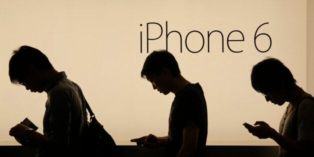 In this photo taken on Friday, Sept. 19, 2014, people wait to buy the new Apple iPhone 6 and 6 Plus devices outside an Apple