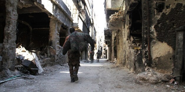 Men walk past destroyed buildings in the Yarmuk Palestinian refugee camp in the Syrian capital Damascus on April 6, 2015. Aro