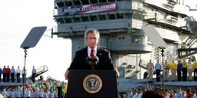 FILE - In this May 1, 2003 file photo, President George W. Bush speaks aboard the aircraft carrier USS Abraham Lincoln off the California coast. As slogans go, President Barack Obama's promise of the âlight of a new dayâ in Afghanistan isn't as catchy as the âMission Accomplishedâ banner that hung across the USS Abraham Lincoln the day President George W. Bush announced the end of major combat operations in Iraq. (AP Photo/J. Scott Applewhite, File)