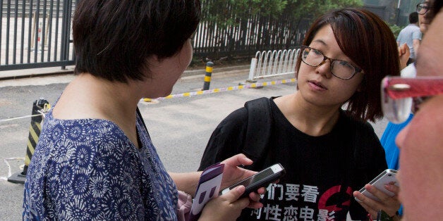 In this photo taken Thursday, July 31, 2014, women's rights activist Wei Tingting, right, waits outside a court where the fir