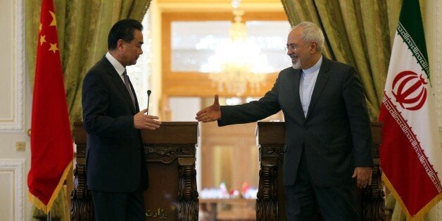 Iranian Foreign Minister Mohammad Javad Zarif (R) and his Chinese counterpart Wang Yi shake hands during a press conference f