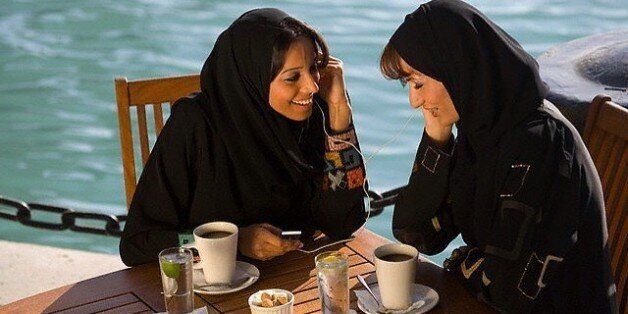 19 Mar 2007, Dubai, United Arab Emirates --- Women Listening to an MP3 Player Over Coffee