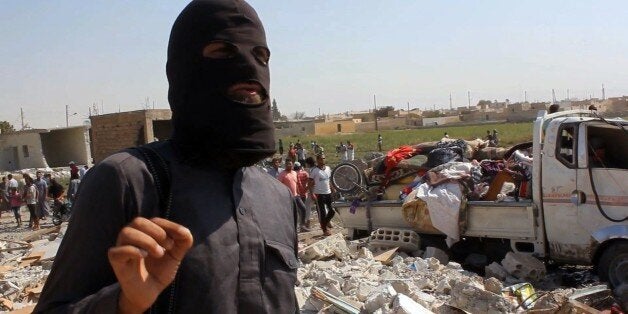 An image grab taken from an AFPTV video on September 16, 2014 shows a jihadist from the Islamic State (IS) group standing on the rubble of houses after a Syrian warplane was reportedly shot down by IS militants over the Syrian town of Raqa. The plane crashed into a house in the Euphrates Valley city, the sole provincial capital entirely out of Syrian government control, causing deaths and injuries on the ground. AFP PHOTO / AFPTV / STR (Photo credit should read -/AFP/Getty Images)