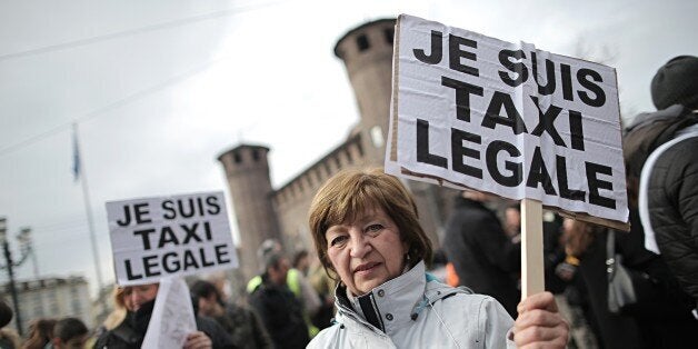 ItalianTaxi drivers hold placards reading 'Je Suis Taxi Legale' (I am a legal taxi) during a demonstration against minicabs and the Taxi app offered by Uber, UberPOP, which they consider being unfair competition, on February 17, 2015 in Turin. AFP PHOTO / MARCO BERTORELLO (Photo credit should read MARCO BERTORELLO/AFP/Getty Images)