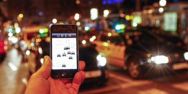 The Uber app is seen on a smartphone past cabs passing on Paseo de Gracia in Barcelona, on December 9, 2014. A judge on Decem