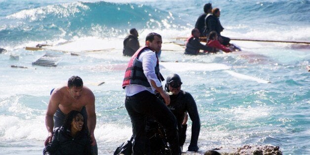 Local residents and rescue workers help a migrant woman after a boat carrying migrants sank off the island of Rhodes, southea
