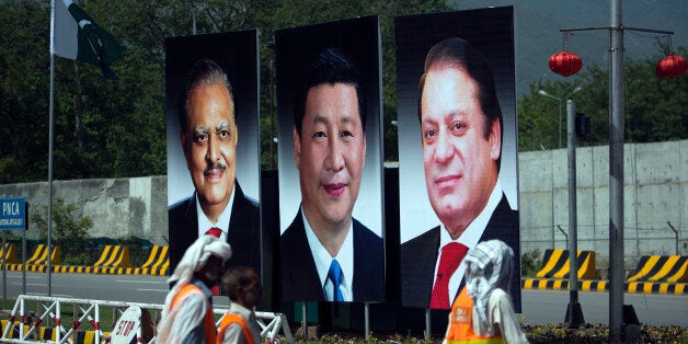 Municipality workers walk past a billboard showing pictures of Chinese President Xi Jinping, center, with Pakistan's President Mamnoon Hussain, left, and Prime Minister Nawaz Sharif on display in Islamabad, Pakistan, Monday, April 20, 2015. Xi arrived for a two-day visit during which the two sides will launch an ambitious $45 billion economic corridor linking Pakistan's port city of Gwadar with western China. (AP Photo/B.K. Bangash)