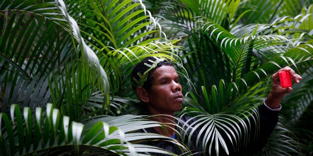 An Orang Asli man, the indigenous minority peoples of Peninsular Malaysia, takes pictures with his mobile phone during a protest against proposed dam projects across the country during ASEAN Power week in Kuala Lumpur, Malaysia, Wednesday, Sept. 10, 2014. The government is proposing 12 mega dams in Sarawak, 16 in Sabab and 3 in Peninsular Malaysia. (AP Photo/Vincent Thian)