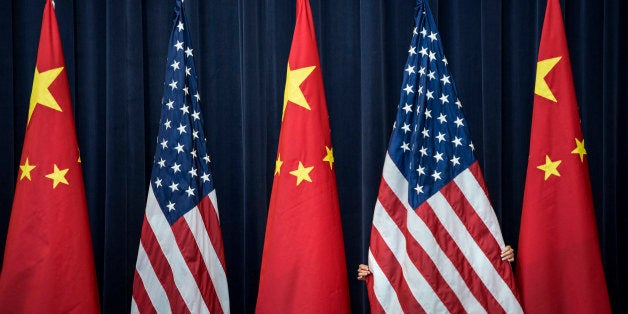 A staff member adjusts an American flag before the opening session of the US and China Strategic and Economic Dialogue at the US Department of State July 10, 2013 in Washington, DC. Officials from the United States and China are meeting in Washington for the 5th US and China Strategic and Economic Dialogue. APF PHOTO/Brendan SMIALOWSKI (Photo credit should read BRENDAN SMIALOWSKI/AFP/Getty Images)