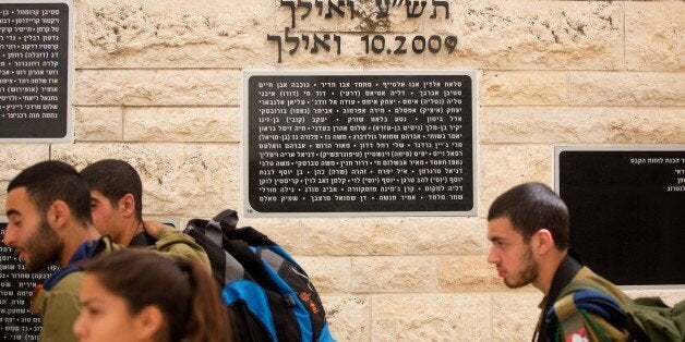 Israeli soldiers walk past a memorial stone in Hebrew bearing the name of Mohammed Abu Khdeir (3rd name from R to L), a Pales