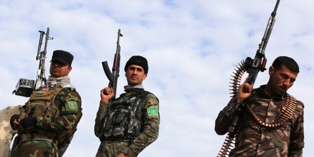Volunteer Shiite fighters who support the government forces in the combat against the Islamic State (IS) group stand in the v