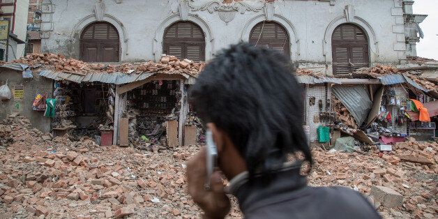 KATHMANDU, NEPAL - APRIL 25: A young man speaks on the phone in front of a collapsed building in the city center following an earthquake on April 25, 2015 in Kathmandu, Nepal. A major 7.8 earthquake hit Kathmandu mid-day on Saturday, and was followed by multiple aftershocks that triggered avalanches on Mt. Everest that buried mountain climbers in their base camps. Many houses, buildings and temples in the capital were destroyed during the earthquake, leaving hundreds dead or trapped under the debris as emergency rescue workers attempt to clear debris and find survivors. (Photo by Omar Havana/Getty Images)