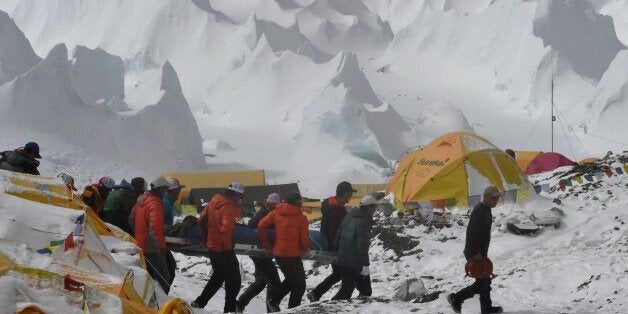 Rescue team personnel carry an injured person towards a waiting rescue helicopter at Everest Base Camp on April 26, 2015, a d