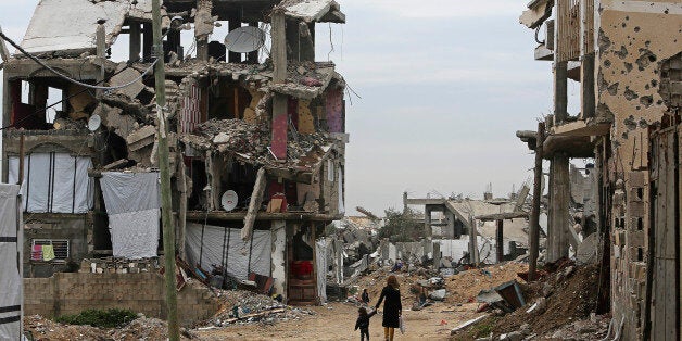Palestinian children walk between the rubble of buildings which were destroyed during the summer 2014 Israel-Hamas war, in th