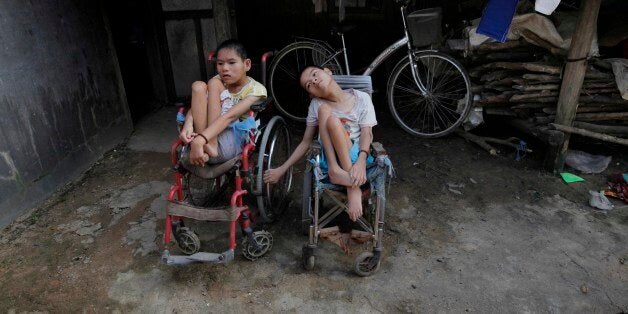 ** ADVANCE FOR SUNDAY, MAY 23 ** In this photo taken on Oct. 5, 2009, Nguyen Thi Tai, left, and Nguyen Thi Thuyet sit together in their wheelchairs outside their family home in the village of Cam Tuyen, Vietnam. The two young women were born with profound physical and mental disabilities that the family, and local officials say, were caused by their parents' exposure to the chemical dioxin in the defoliant Agent Orange. (AP Photo/David Guttenfelder)