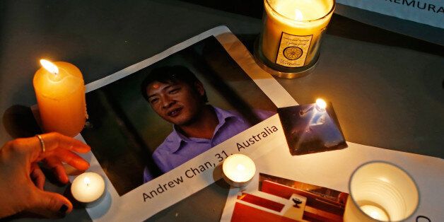 SYDNEY, AUSTRALIA - APRIL 28: A woman places a candle on top of a picture of Australian Andrew Chan, one of one of the prisoners to be executed in Indonesia, during a vigil at Martin Place on April 28, 2015 in Sydney, Australia. Supporters of Bali Nine duo Andrew Chan and Myuran Sukumaran held a vigil tonight as the pair prepare to face the firing squad this evening at Indonesia's Nusakambangan Island. Chan and Sukumaran were both sentenced to death after being found guilty of attempting to smuggle 8.3kg of heroin valued at around $4 million from Indonesia to Australia along with 7 other accomplices. (Photo by Daniel Munoz/Getty Images)