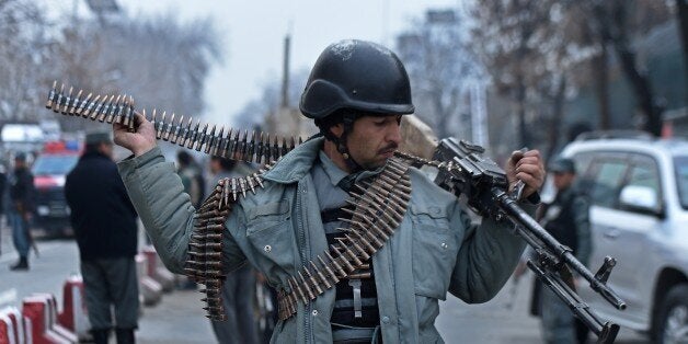 An Afghan policeman adjusts his weapon as he stands at the scene of a suicide attack on a Turkish diplomatic vehicle in front