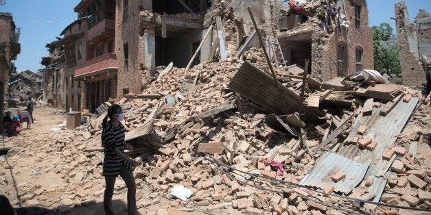 A Nepalese woman walks next to damaged homes in Sankhu town in the Kathmandu Valley on May 3, 2015, following a 7.8 magnitude earthquake which struck the Himalayan nation on April 25. The death toll from an earthquake that ripped through Nepal will climb 'much higher', the government warned May 3, as relief teams raced to reach survivors of the disaster that has already claimed more than 7,000 lives. AFP PHOTO /MENAHEM KAHANA (Photo credit should read MENAHEM KAHANA/AFP/Getty Images)