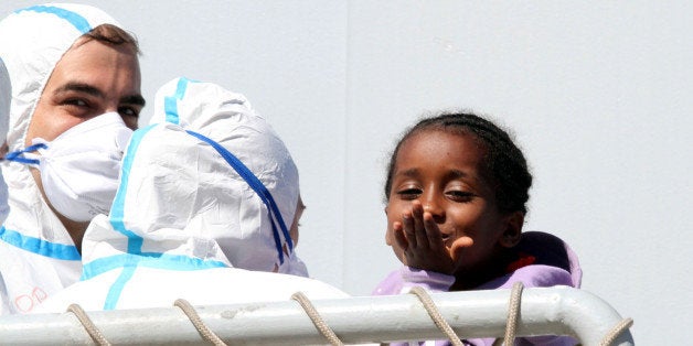 A child blows a kiss as migrants disembark from the Italian Navy frigate Bersagliere at the Reggio Calabria harbor, Italy, Monday, May 4, 2015. Italy's Coast Guard and Navy as well as tugs and other commercial vessels joined forces to rescue migrants in at least 16 boats Sunday, saving hundreds of them and recovering 10 bodies off Libya's coast, as smugglers took advantage of calm seas to send packed vessels across the Mediterranean. Sunday's drama at sea came a day after 3,690 migrants were saved from smugglers' boats. Most of those migrants are still being taken to southern Italian ports even as the fresh rescues were taking place. (AP Photo/Adriana Sapone)