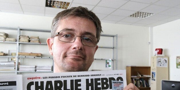 FILE - In this Sept.19, 2012 file photo, Stephane Charbonnier also known as Charb , the publishing director of the satyric weekly Charlie Hebdo, displays the front page of the newspaper as he poses for photographers in Paris. The late former editor of French weekly Charlie Hebdo takes on politicians, the media and "Islamophobia" as thinly veiled racism in a posthumously published book that was completed two days before he died in France's worst terror attack in years. (AP Photo/Michel Euler, File)