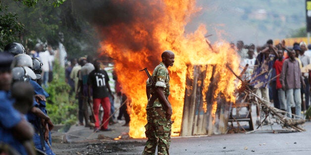 A soldier stands between demonstrators and riot police facing off in the Musaga district of Bujumbura, Burundi, Monday May 4, 2015. Anti-government demonstrations resumed in Burundi's capital after a weekend pause as thousands continue to protest the president's decision to seek a third term. (AP Photo/Jerome Delay)