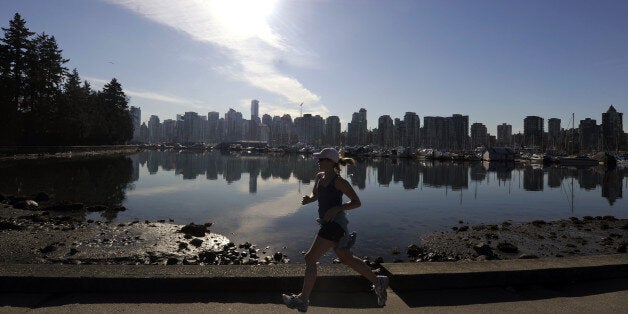 A woman joggs in Stanley Park in front of the Vancouver Skyline on February 19, 2010, during the Vancouver Winter Olympics. AFP PHOTO DDP / DAVID HECKER (Photo credit should read DAVID HECKER/AFP/Getty Images)