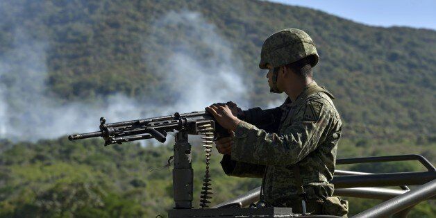 A soldier of the 88 infantry brigade observes as smoke raises after a military helicopter was shot down in Villa Vieja community, Villa Purificacion, Jalisco State, Mexico on May 2, 2015. Mexican authorities searched Saturday for three missing soldiers after gunmen brought down their helicopter in a field during an antinarcotics cartel operation that sparked mayhem in Jalisco state. AFP PHOTO / Yuri COREZ (Photo credit should read YURI CORTEZ/AFP/Getty Images)