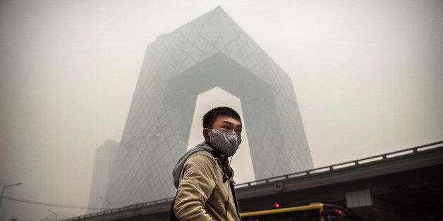 BEIJING, CHINA - NOVEMBER 29: A Chinese man wears a mask as he waits to cross the road near the CCTV building during heavy smog on November 29, 2014 in Beijing, China. United States President Barack Obama and China's president Xi Jinping agreed on a plan to limit carbon emissions by their countries, which are the world's two biggest polluters, at a summit in Beijing earlier this month. (Photo by Kevin Frayer/Getty Images)
