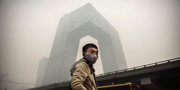 BEIJING, CHINA - NOVEMBER 29: A Chinese man wears a mask as he waits to cross the road near the CCTV building during heavy s