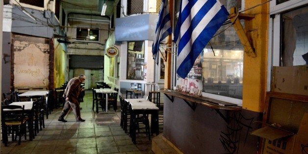 A man walks past a Greek flag in the central market of the northern port city of Thessaloniki , Greece, Wednesday, April 29, 2015. Greece is to present a draft bill of reforms to creditors Wednesday in the hope it will earn their approval and pave the way for the unlocking of vitally needed bailout funds. (AP Photo/Giannis Papanikos)