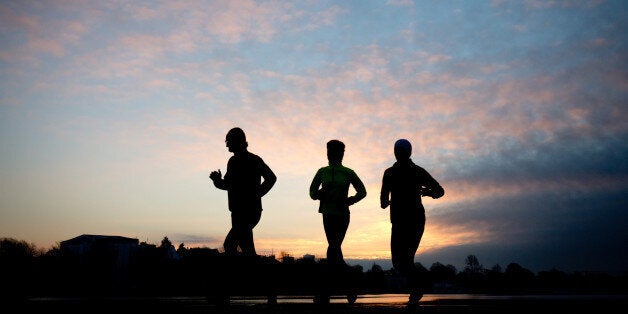 Three runners are silhouetted as they run past the Aussenalster lake in Hamburg, northern Germany, Wednesday morning, Feb. 4, 2015. (AP Photo/dpa, Christian Charisius)